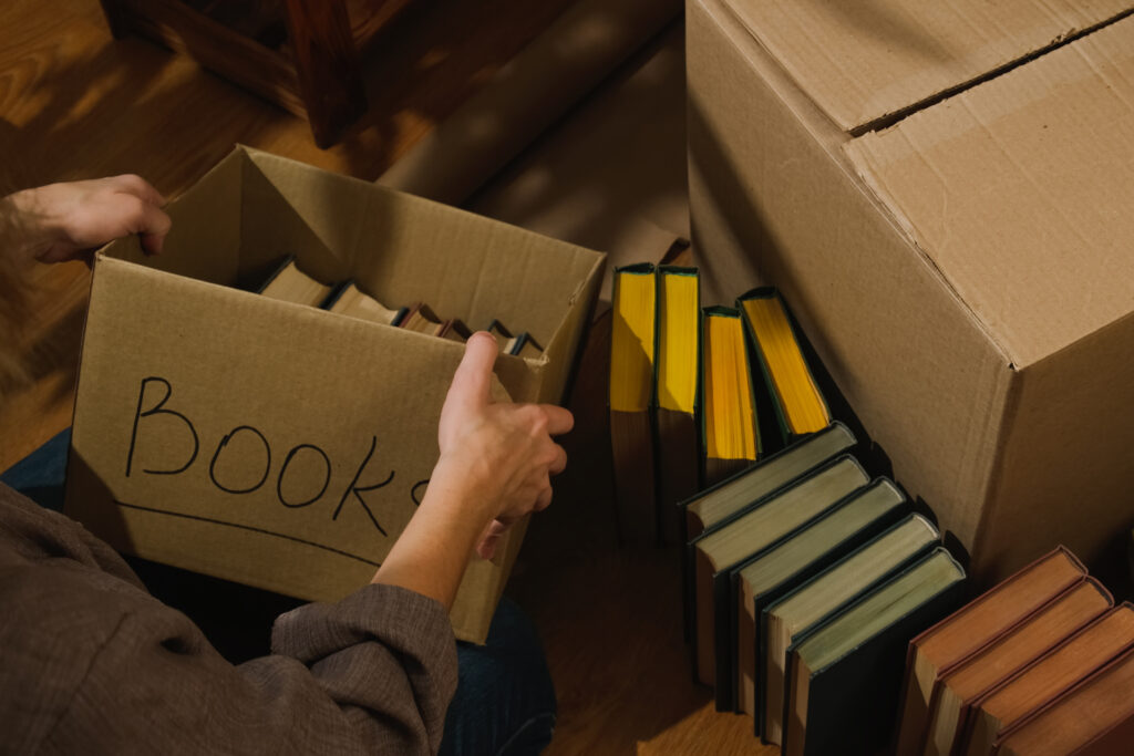 Household moving. Unpacking books in new flat. Woman open moving boxes.